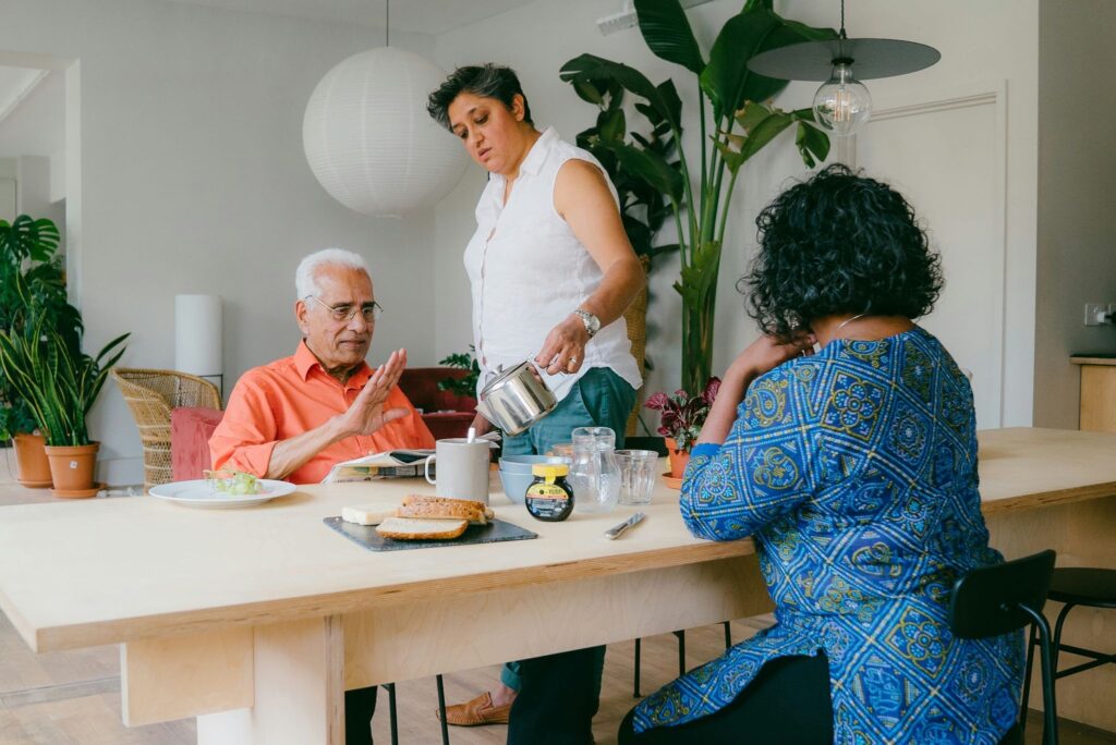 Adult child pouring cup of coffee for her father.